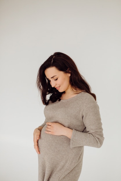 Free photo beautiful young pregnant woman posing in studio in dress