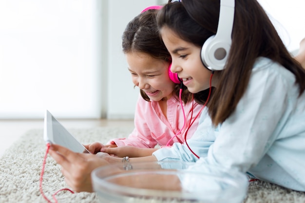 Beautiful young sisters listening to music with digital tablet a