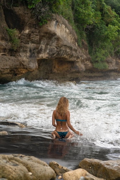 Free photo beautiful young slender woman with long blond hair in a swimsuit on the beach near the ocean. relax on the beach. tropical vacations.