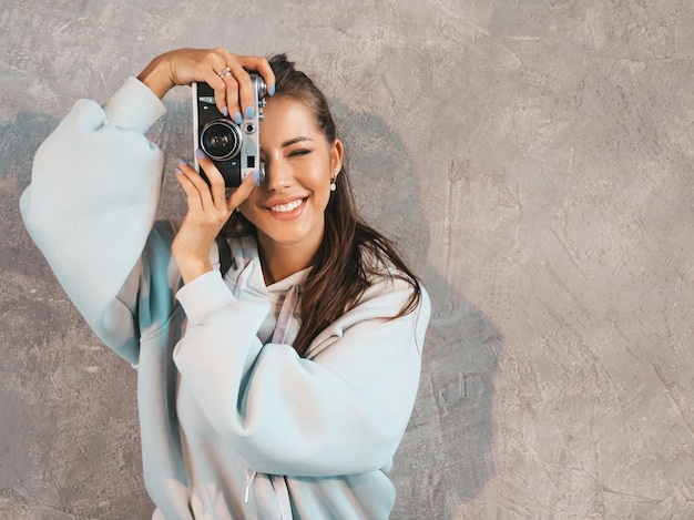 Free photo beautiful young smiling photographer girl taking photos using her retro camera.