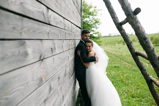 Free photo beautiful young wedding couple stands near the old wooden house