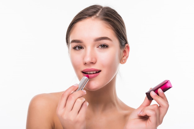 Free photo beautiful young woman applying chapstick to lips isolated over white wall.