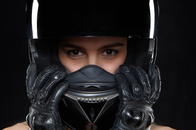 Free photo beautiful young woman in black leather gloves and protective motorbike helmet. attractive self determined female motocycle racer wearing hands and body protection from falls and accidents