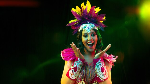 Beautiful young woman in carnival mask, stylish masquerade costume with feathers and sparklers inviting