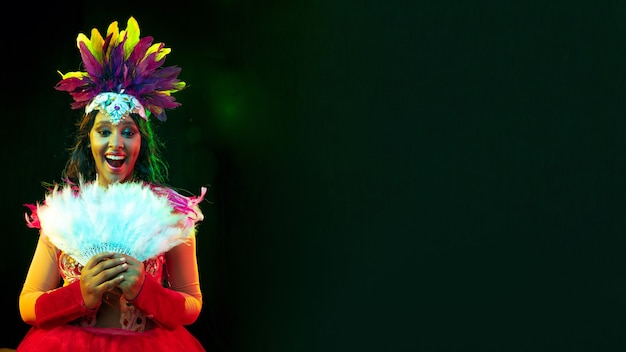 Beautiful young woman in carnival mask, stylish masquerade costume with feathers and sparklers inviting.