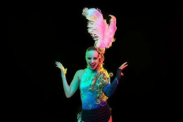 Free photo beautiful young woman in carnival and masquerade costume in colorful neon lights on black