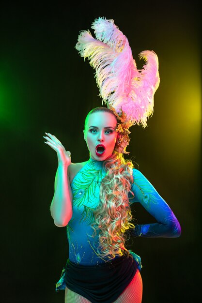 Beautiful young woman in carnival and masquerade costume in colorful neon lights