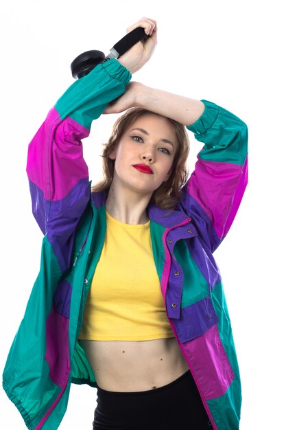 Beautiful young woman in colorful jacket and holding headphones