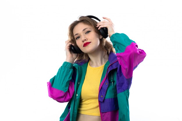 Beautiful young woman in colorful jacket and holding headphones