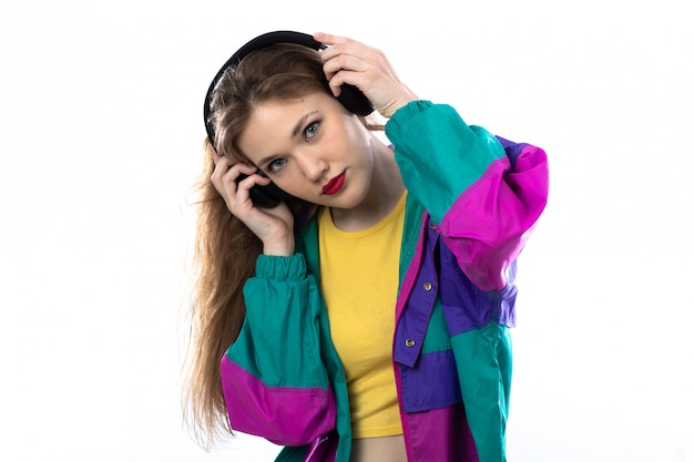 Beautiful young woman in colorful jacket and holding headphones