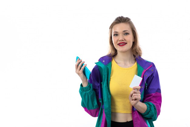 Beautiful young woman in colorful jacket using smartphone and credit card