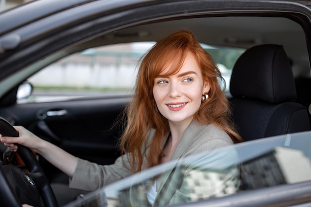 Beautiful young woman driving her new car at sunset Woman in car Close up portrait of pleasant looking female with glad positive expression woman in casual wear driving a car