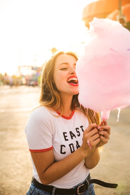 Free Photo beautiful young woman eating pink candy floss