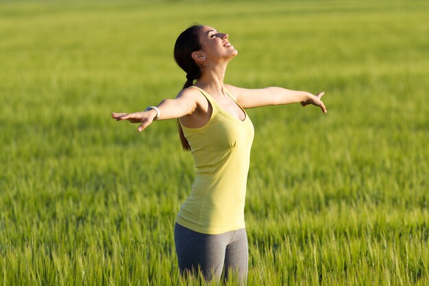 Beautiful young woman enjoying the spring standing in a cereal field