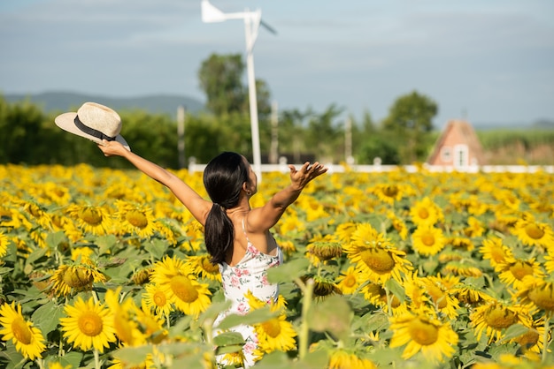 Free photo beautiful young woman in a field of sunflowers in a white dress. travel on the weekend concept. portrait of authentic woman in straw hat . outdoors on the sunflower field.