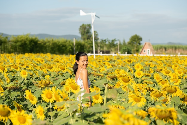 Beautiful young woman in a field of sunflowers in a white dress. travel on the weekend concept. portrait of authentic woman in straw hat . Outdoors on the sunflower field.