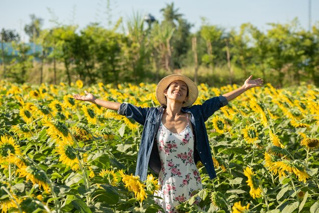 Beautiful young woman in a field of sunflowers in a white dress. travel on the weekend concept. portrait of authentic woman in straw hat . Outdoors on the sunflower field.