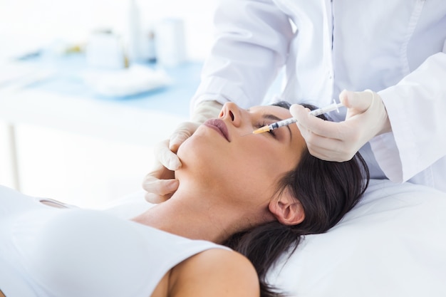 Free Photo beautiful young woman getting botox cosmetic injection in her face.