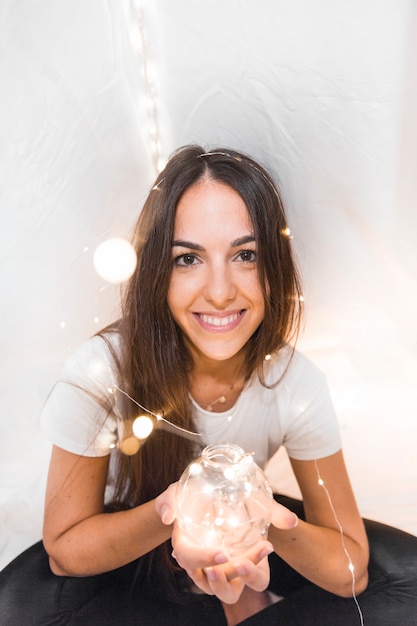 Free photo beautiful young woman holding glowing sphere with ferry lights on her head