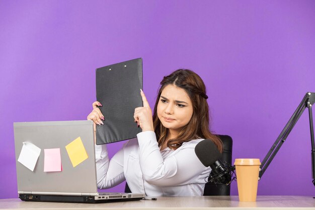 A beautiful young woman holding her notebook and looking at pc screen High quality photo