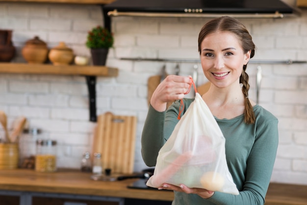 Beautiful young woman holding reusable groceries bag