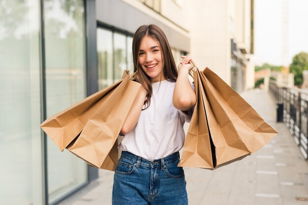 Beautiful young woman holding shopping bags and smiling outdoors