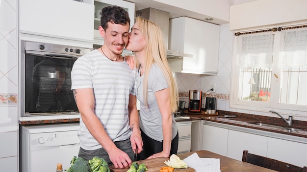 Free photo beautiful young woman loving her husband cutting broccoli in the kitchen