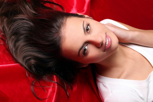 Beautiful young woman lying in red silk, top view