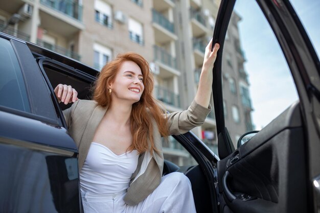 Beautiful young woman opens the car door Attractive woman getting out of the car