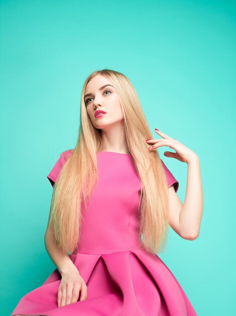 The beautiful young woman in pink mini dress posing 