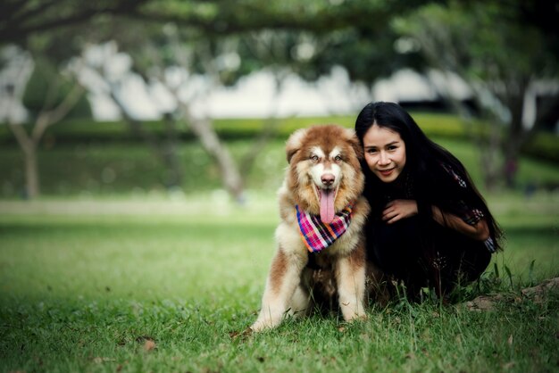 Beautiful young woman playing with her little dog in a park outdoors. Lifestyle portrait.