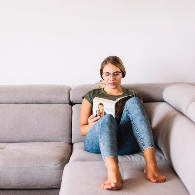 Beautiful young woman reading book at home