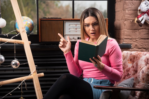 Free Photo beautiful young woman reading book intensely at home.