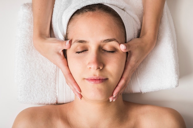 Beautiful young woman receiving facial massage with closed eyes in a spa salon