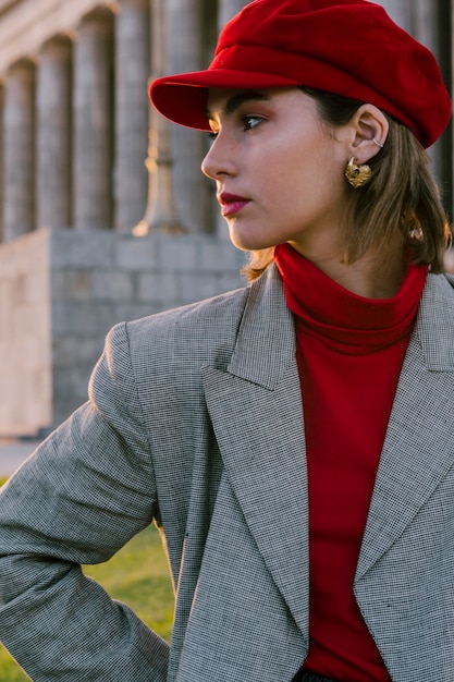 Free Photo beautiful young woman in red cap with golden earring in her ears looking away