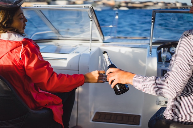 Free Photo beautiful young woman in a red cloak drinking champagne on a yacht.