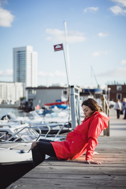 Free photo beautiful young woman in a red cloak in the yacht port. stockholm, sweden