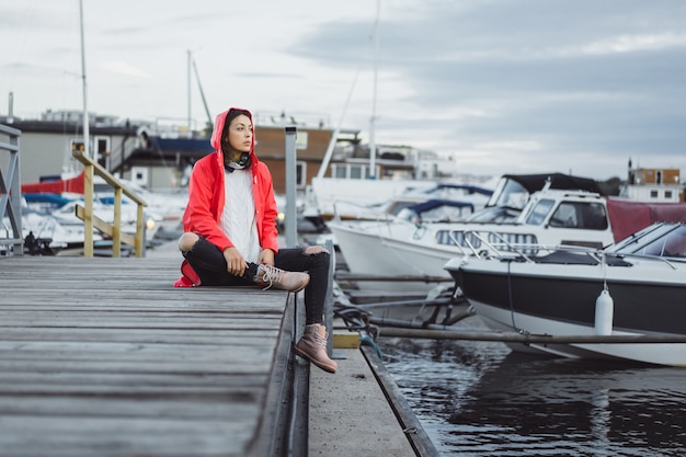 Beautiful young woman in a red cloak in the yacht port. Stockholm, Sweden