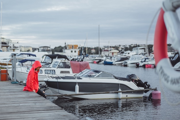 Free photo beautiful young woman in a red cloak in the yacht port. stockholm, sweden