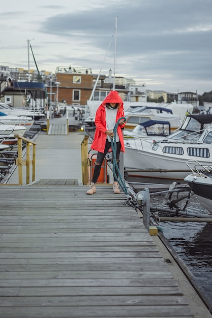 Beautiful young woman in a red cloak in the yacht port. Stockholm, Sweden