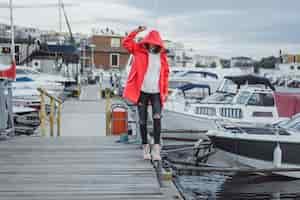 Free photo beautiful young woman in a red cloak in the yacht port. stockholm, sweden