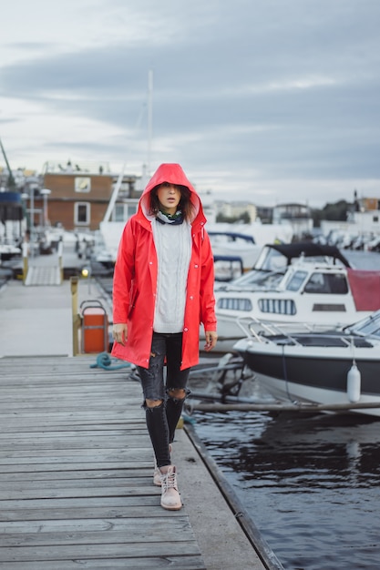 Free photo beautiful young woman in a red cloak in the yacht port. stockholm, sweden