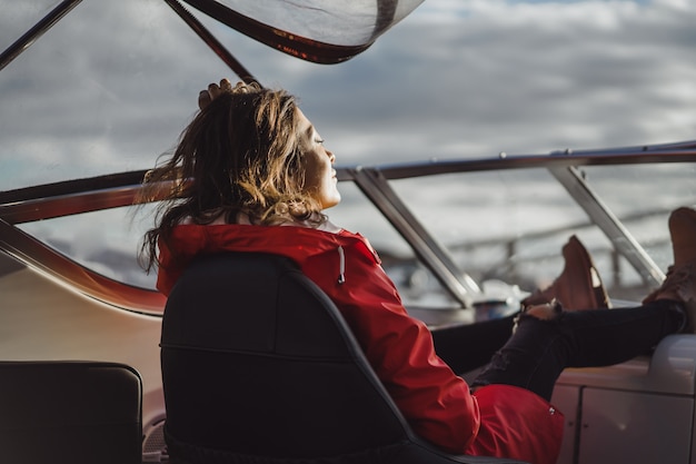 beautiful young woman in a red raincoat rides a private yacht. Stockholm, Sweden