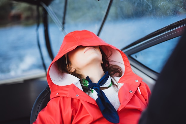 beautiful young woman in a red raincoat rides a private yacht. Stockholm, Sweden