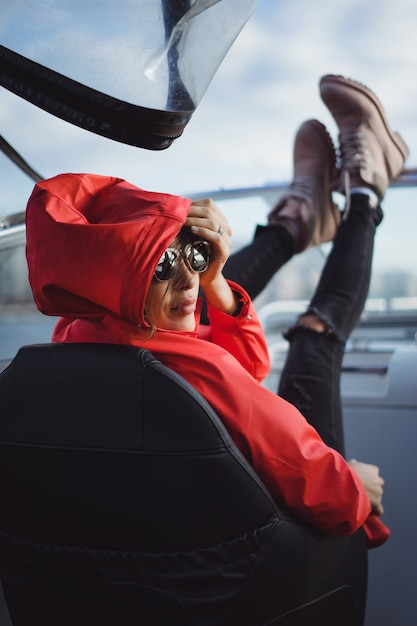 beautiful young woman in a red raincoat rides a private yacht. Stockholm, Sweden