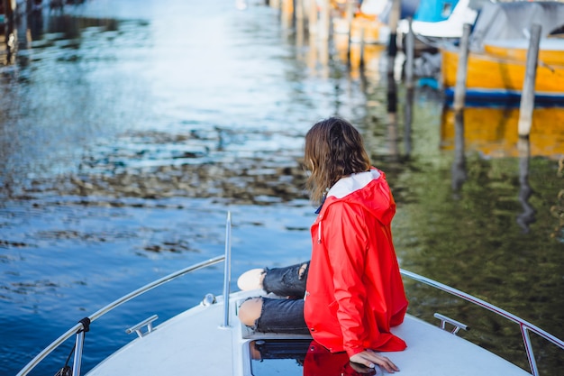 beautiful young woman in a red raincoat rides a private yacht. Stockholm, Sweden