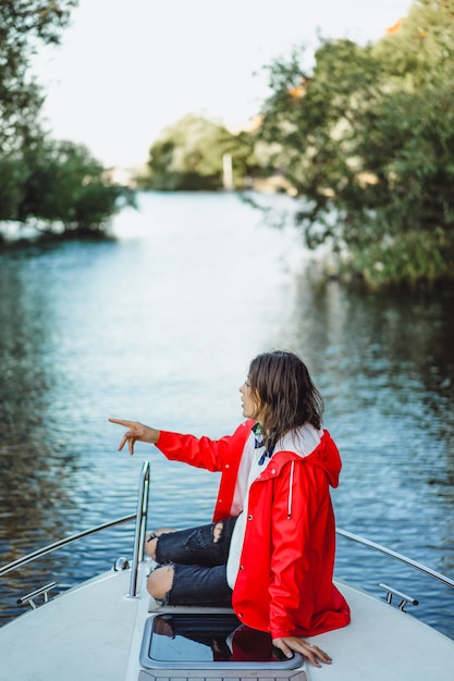 beautiful young woman in a red raincoat rides a private yacht. Stockholm, Sweden