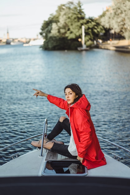 Free Photo beautiful young woman in a red raincoat rides a private yacht. stockholm, sweden