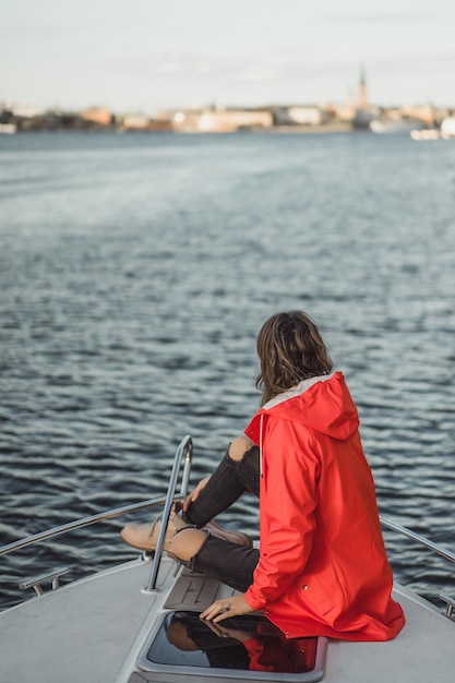 Free Photo beautiful young woman in a red raincoat rides a private yacht. stockholm, sweden