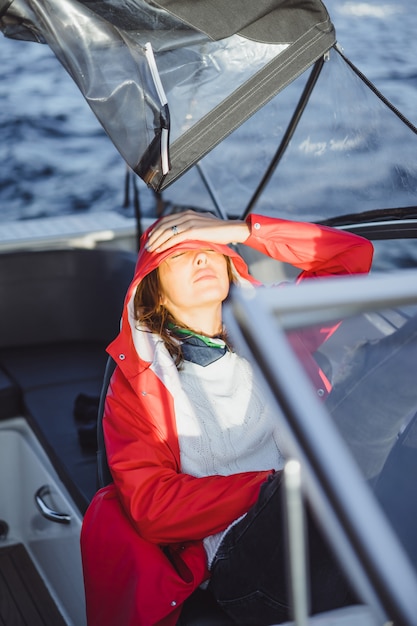 Free Photo beautiful young woman in a red raincoat rides a private yacht. stockholm, sweden